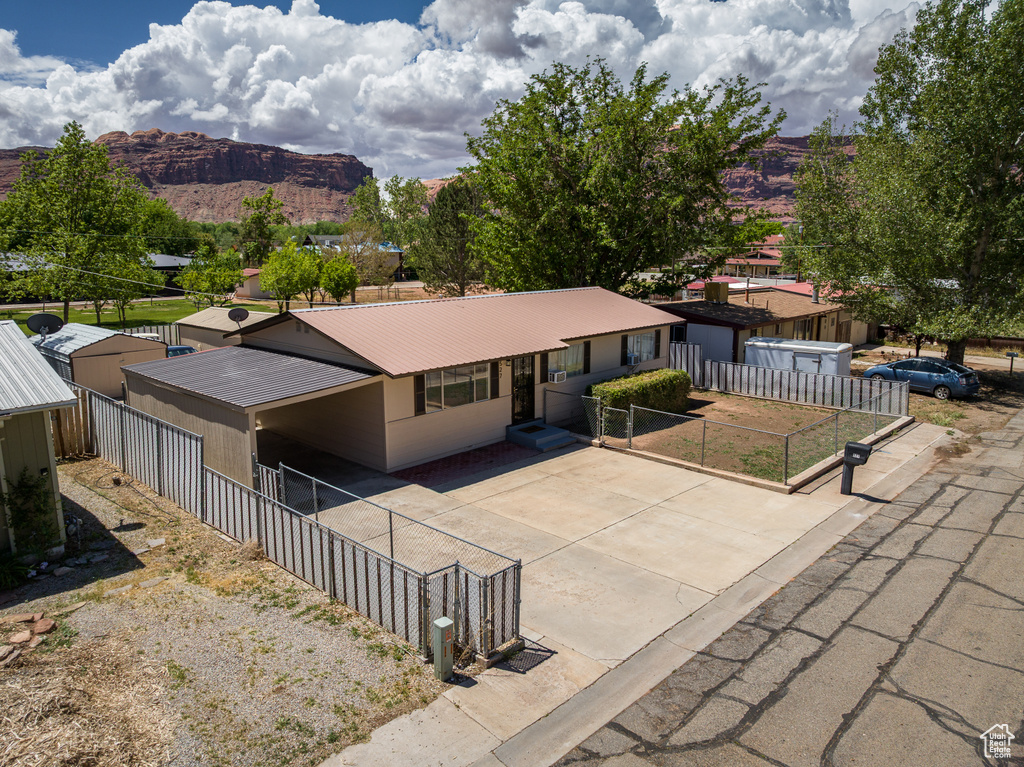 Single story home featuring a mountain view, metal roof, fence, and driveway