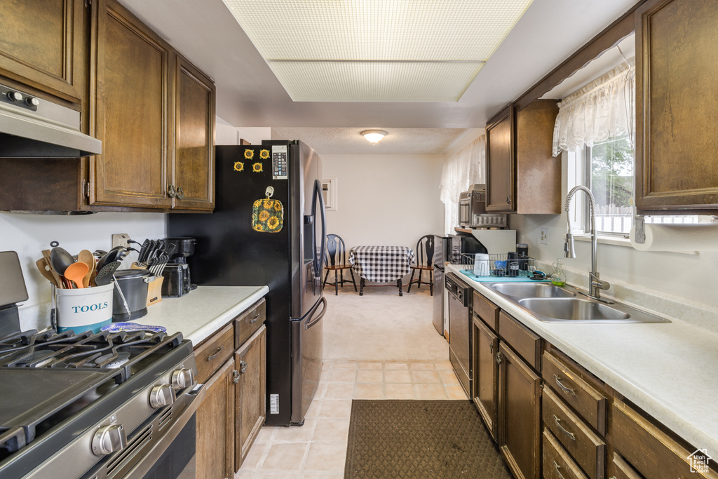 Kitchen featuring stainless steel appliances, a sink, light colored carpet, and light countertops