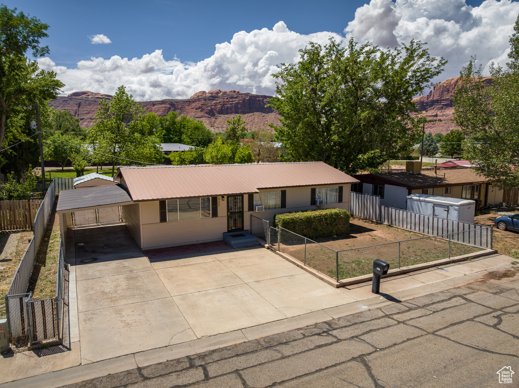 Single story home with a mountain view, driveway, a fenced front yard, metal roof, and an attached carport
