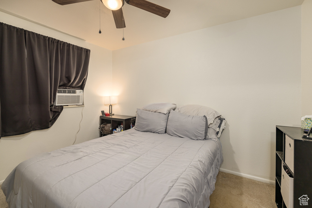 Carpeted bedroom with a ceiling fan, baseboards, and cooling unit