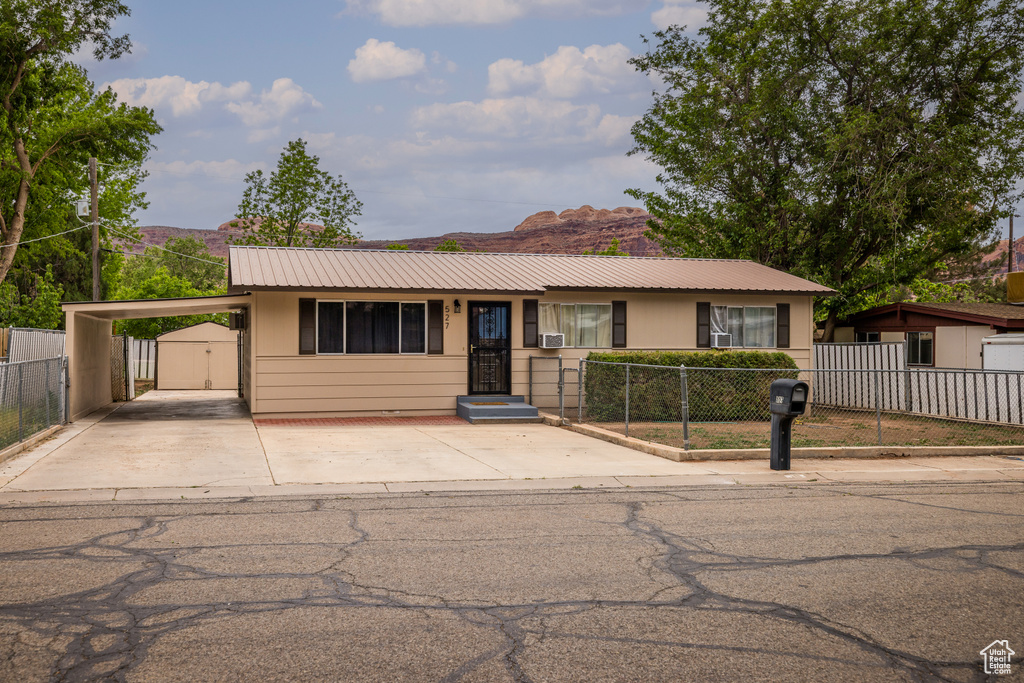 Single story home with driveway, metal roof, an attached carport, a mountain view, and a gate