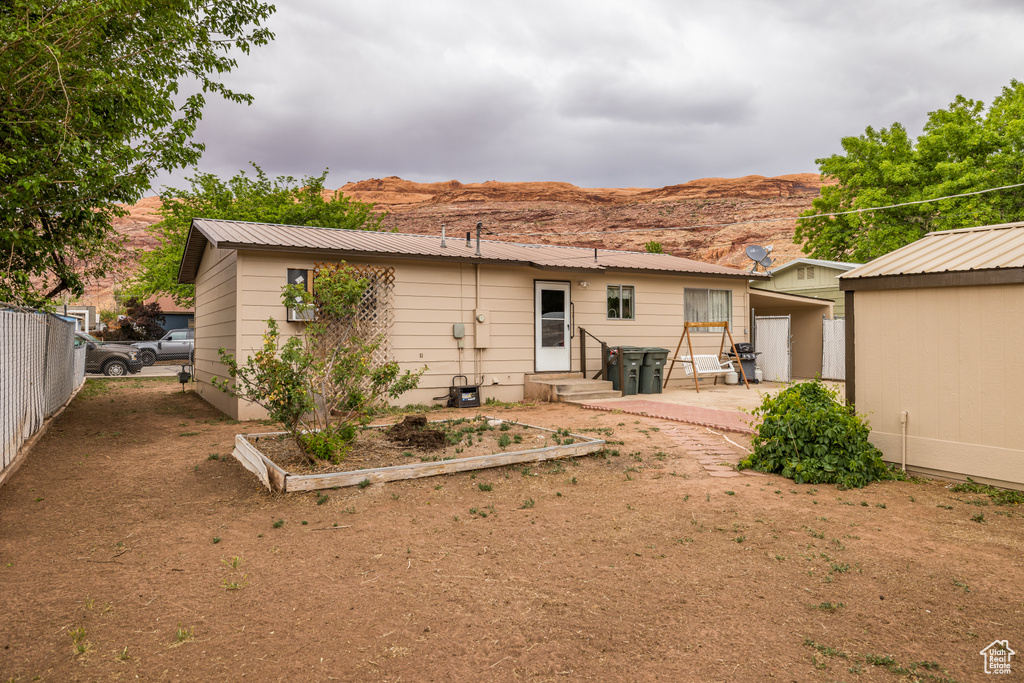 Rear view of house with fence, a patio area, metal roof, and a mountain view