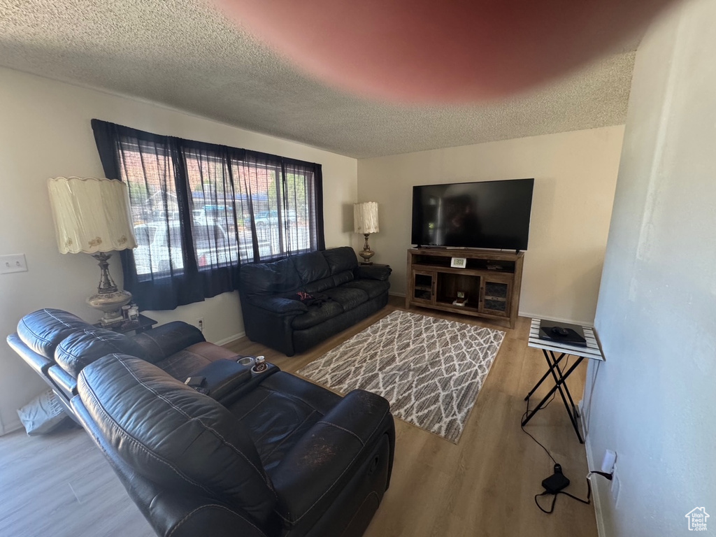 Living area with a textured ceiling, wood finished floors, and baseboards