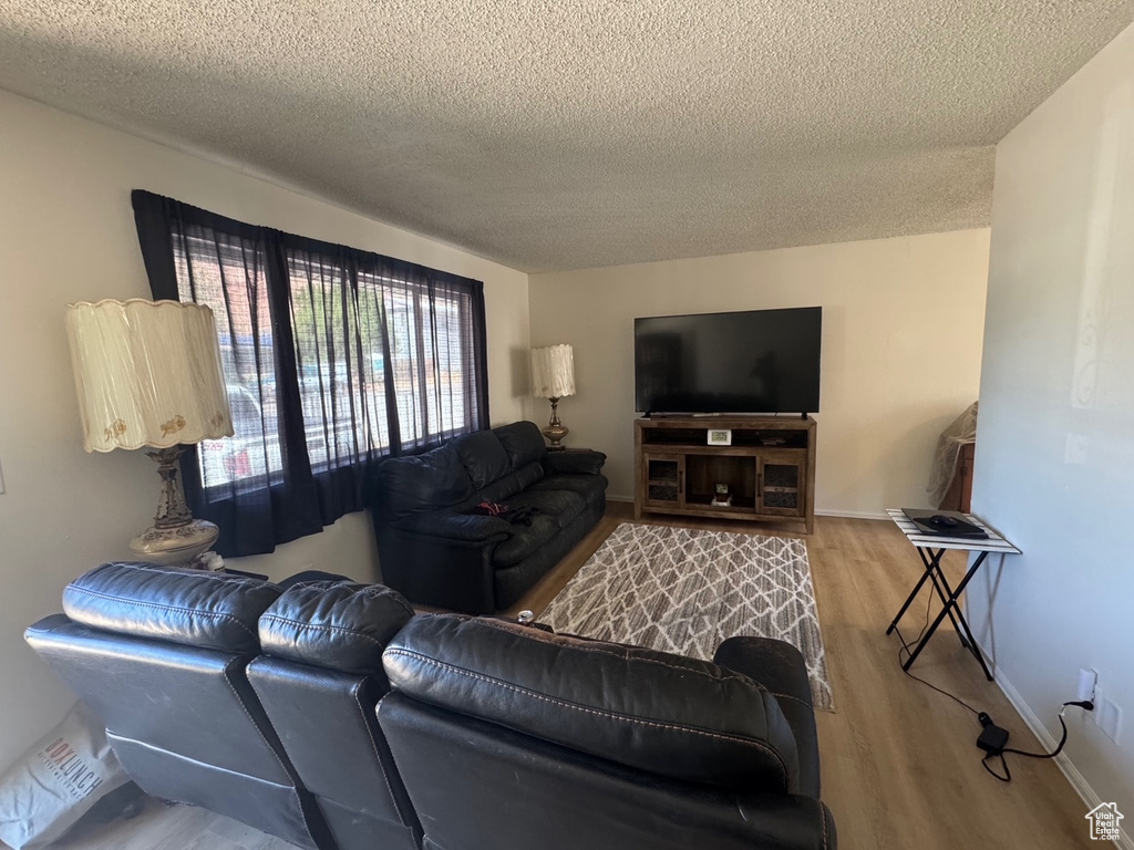 Living area with a textured ceiling, wood finished floors, and baseboards