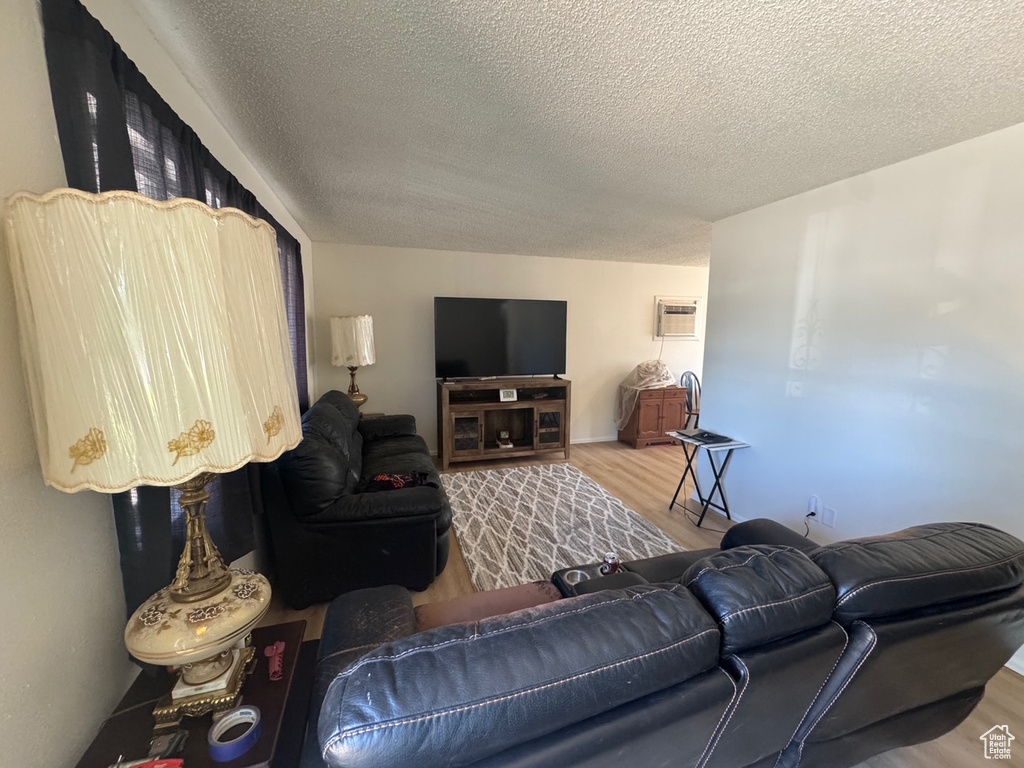 Living room featuring wood finished floors, a textured ceiling, and a wall mounted AC