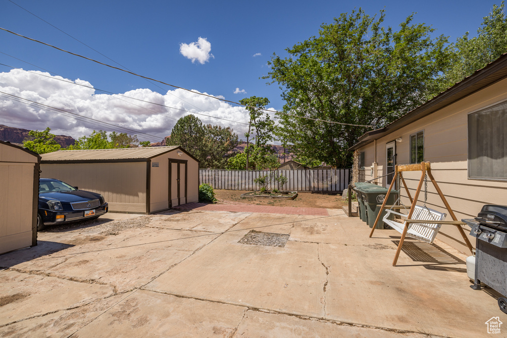 View of patio / terrace with a storage unit, a fenced backyard, and an outdoor structure