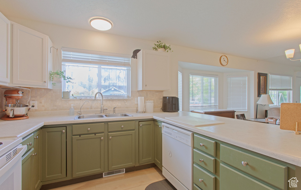 Kitchen featuring a sink, green cabinetry, a healthy amount of sunlight, visible vents, and dishwasher