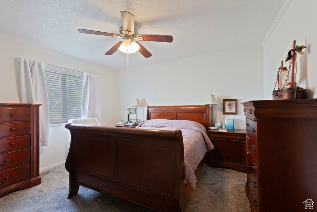 Carpeted bedroom featuring ceiling fan and crown molding