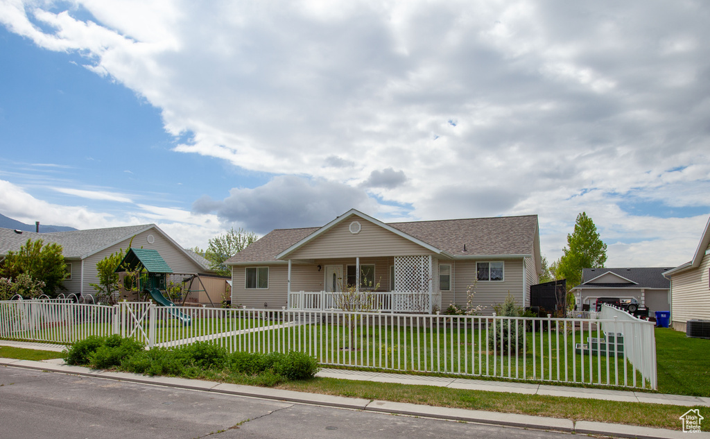 View of front of house with a fenced front yard, covered porch, a front yard, roof with shingles, and a playground