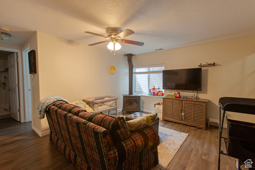Living area with baseboards, ceiling fan, a textured ceiling, and wood finished floors