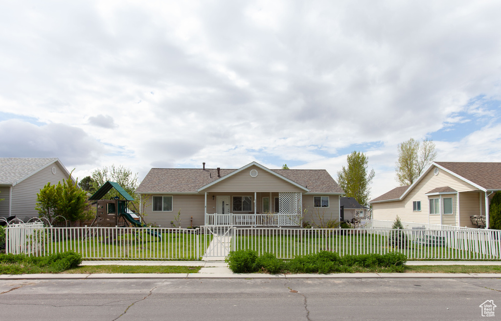 View of front of home featuring a fenced front yard, a porch, roof with shingles, a front lawn, and a playground