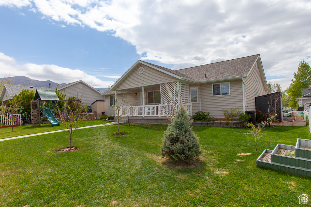 Ranch-style house featuring fence, covered porch, a garden, a front yard, and a playground