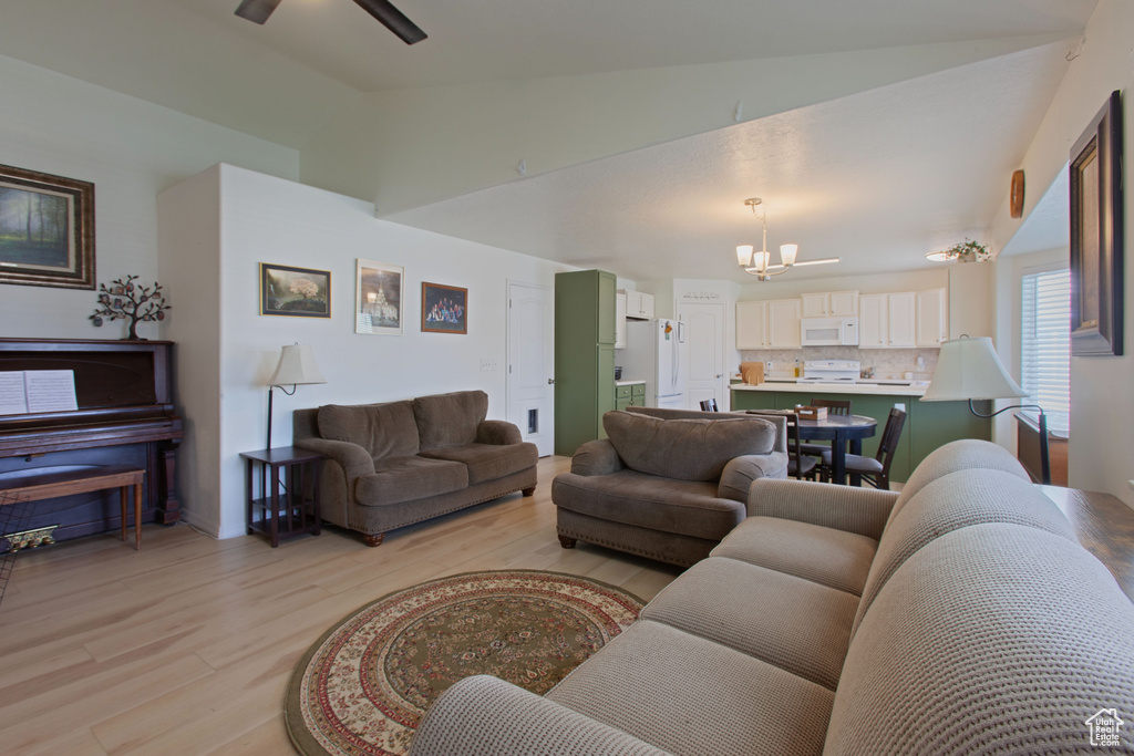 Living area featuring high vaulted ceiling, light wood-type flooring, and ceiling fan with notable chandelier