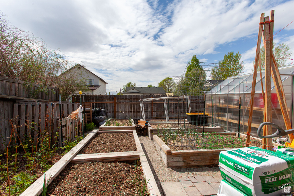 View of yard featuring a vegetable garden, an outdoor structure, a fenced backyard, and a greenhouse