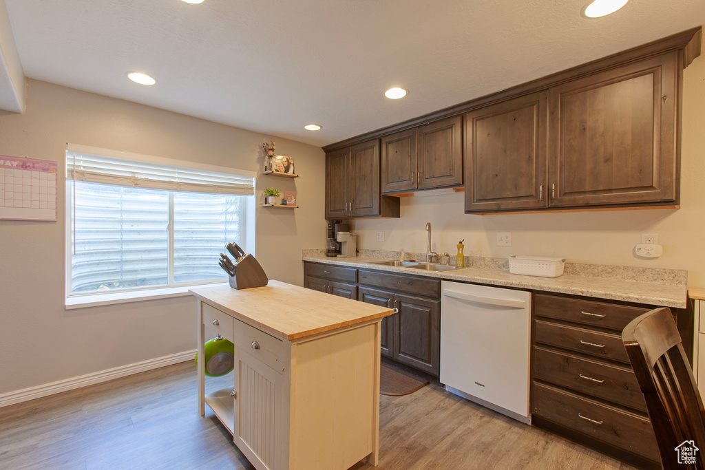 Kitchen with white dishwasher, light wood finished floors, recessed lighting, and a sink