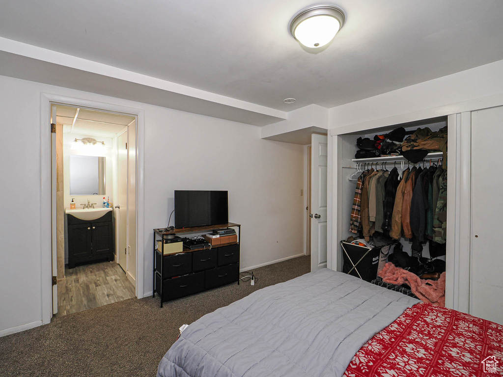 Carpeted bedroom featuring a closet, a sink, and baseboards