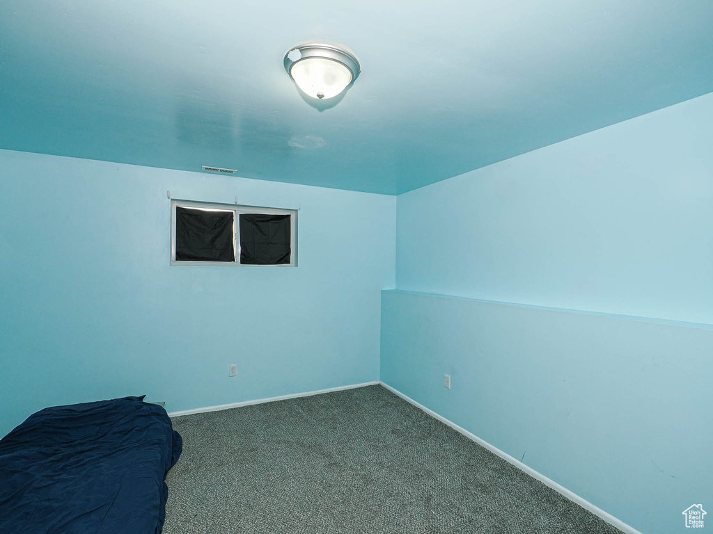 Spare room with baseboards and dark carpet