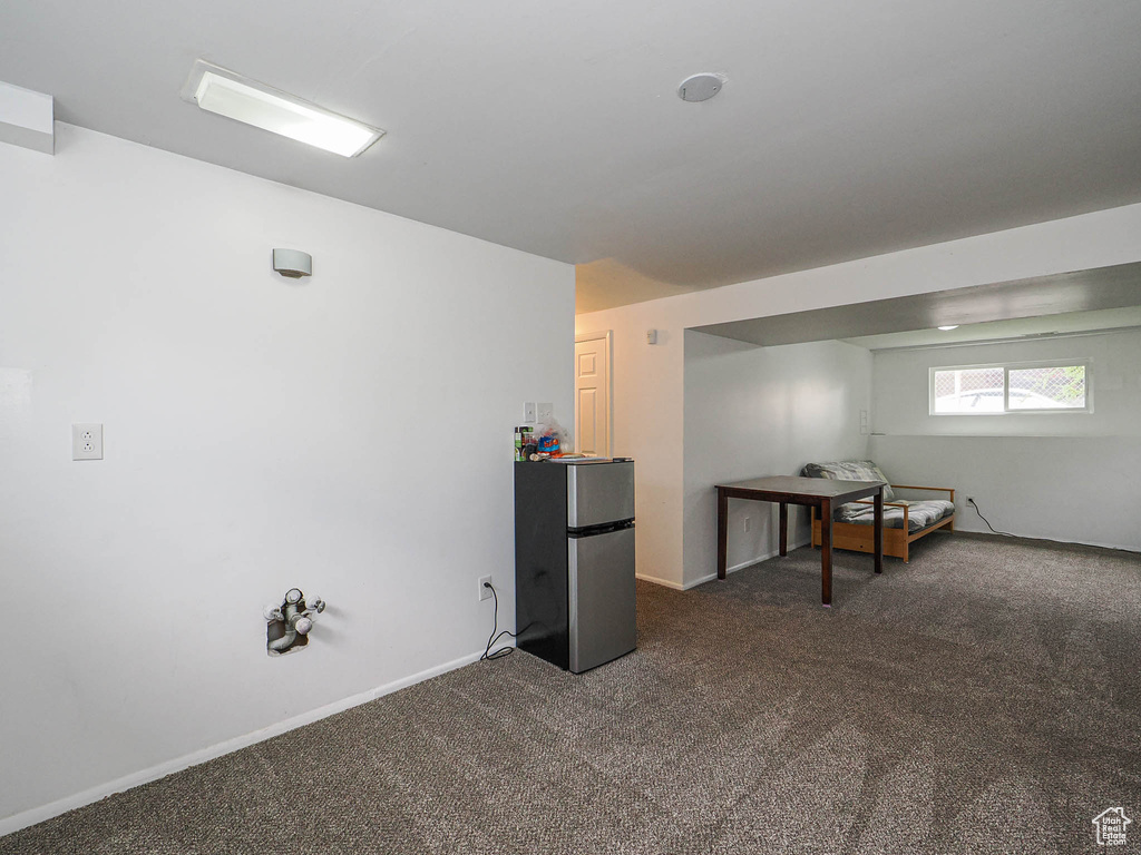 Below grade area with freestanding refrigerator, dark carpet, and baseboards