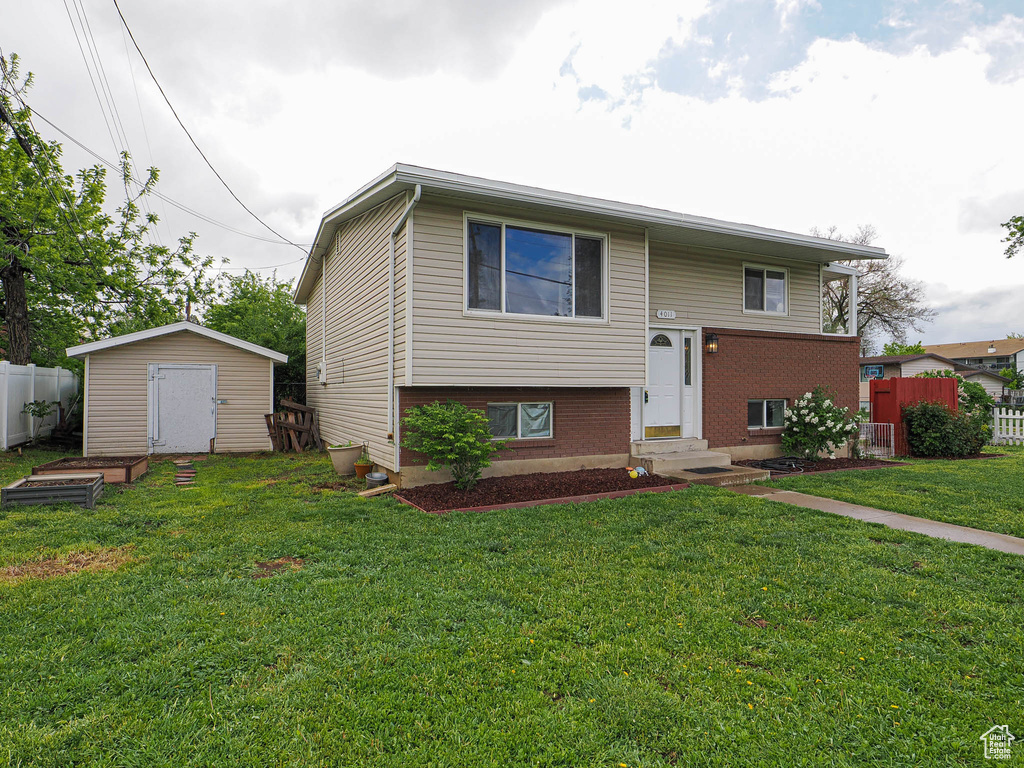 Raised ranch with entry steps, brick siding, a storage shed, and an outdoor structure