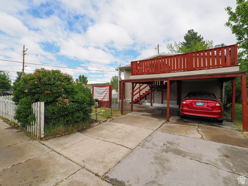 View of parking / parking lot featuring stairway, a carport, fence, and driveway