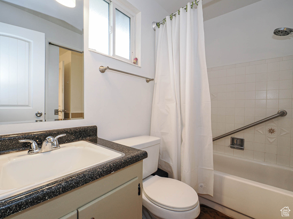 Bathroom featuring toilet, vanity, and shower / bath combo with shower curtain