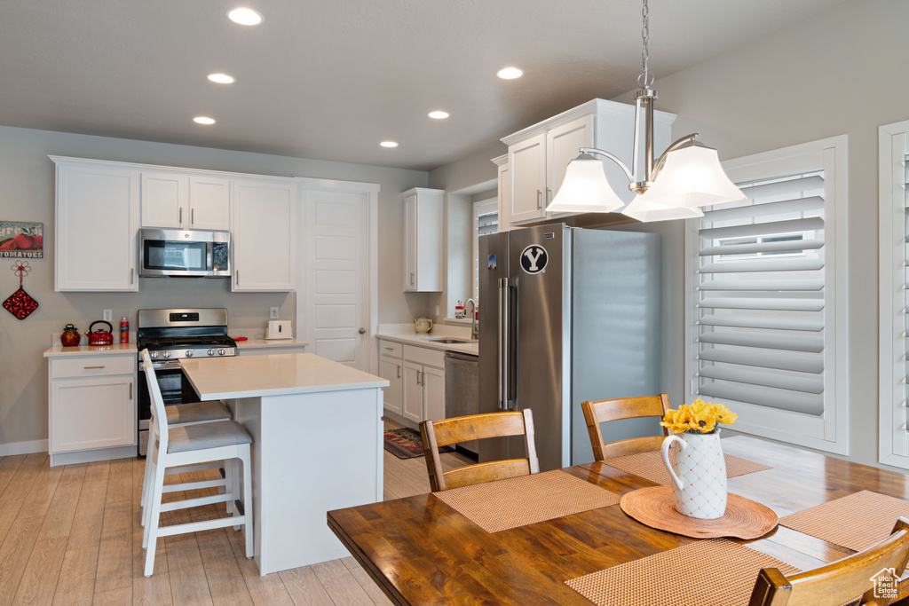 Kitchen featuring appliances with stainless steel finishes, light wood-style flooring, a center island, white cabinets, and recessed lighting