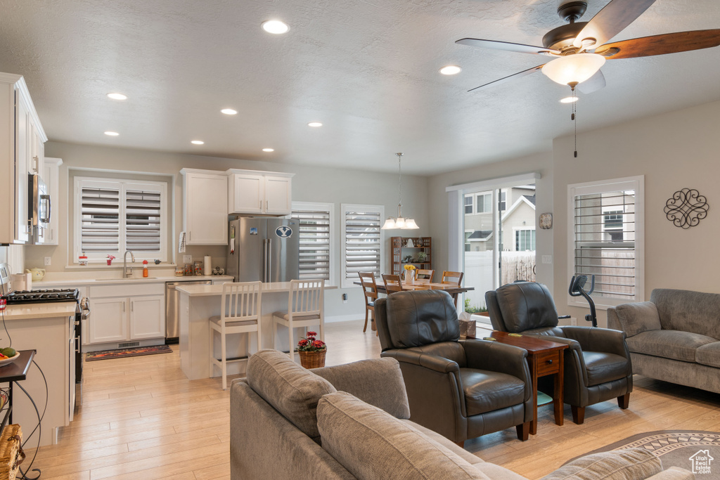 Living room with a ceiling fan, light wood finished floors, and recessed lighting