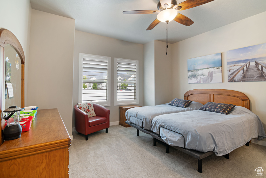 Bedroom with light carpet, a ceiling fan, and baseboards