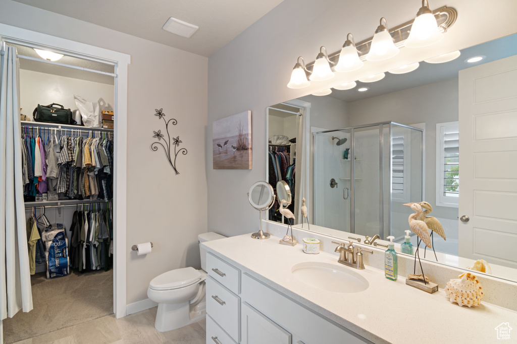 Bathroom featuring vanity, a stall shower, toilet, and a walk in closet