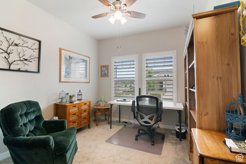 Office area featuring light carpet, ceiling fan, and baseboards