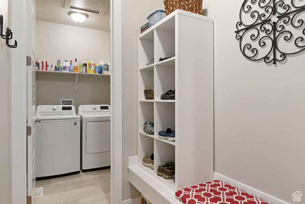 Washroom with washer and clothes dryer and light wood-type flooring
