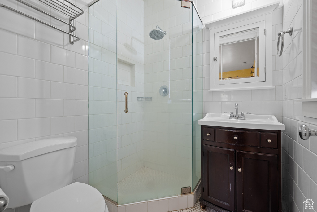 Bathroom featuring tile walls, toilet, a stall shower, and vanity