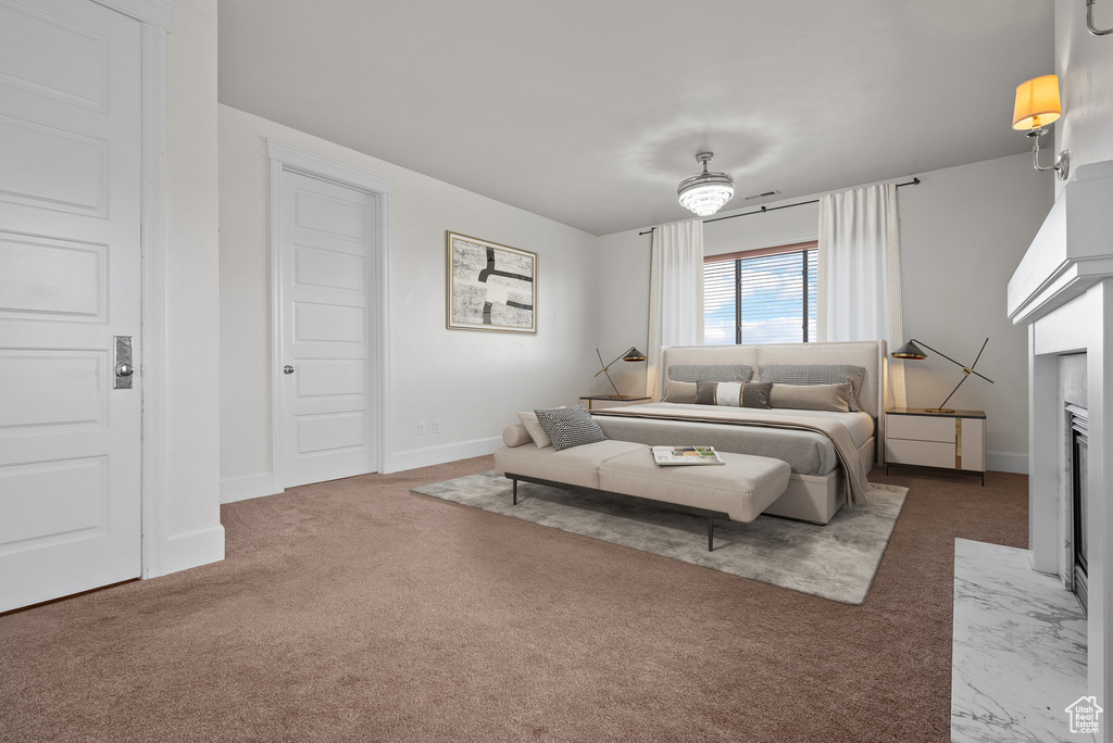 Carpeted bedroom featuring baseboards and a fireplace
