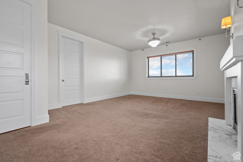 Unfurnished living room with a fireplace with flush hearth, carpet floors, and baseboards