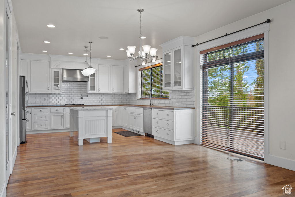 Kitchen featuring backsplash, wall chimney range hood, a chandelier, and appliances with stainless steel finishes