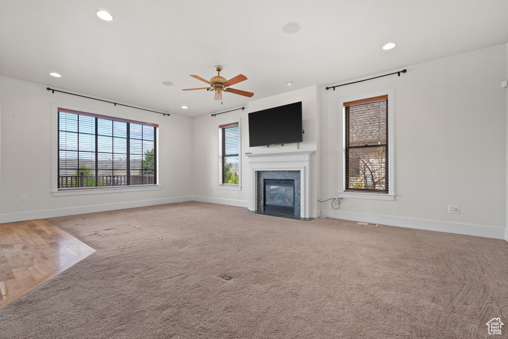 Unfurnished living room with a ceiling fan, a fireplace with flush hearth, baseboards, light colored carpet, and recessed lighting