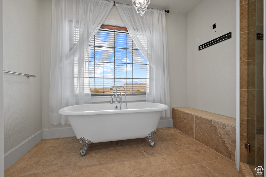 Full bath featuring a freestanding bath, plenty of natural light, and a chandelier