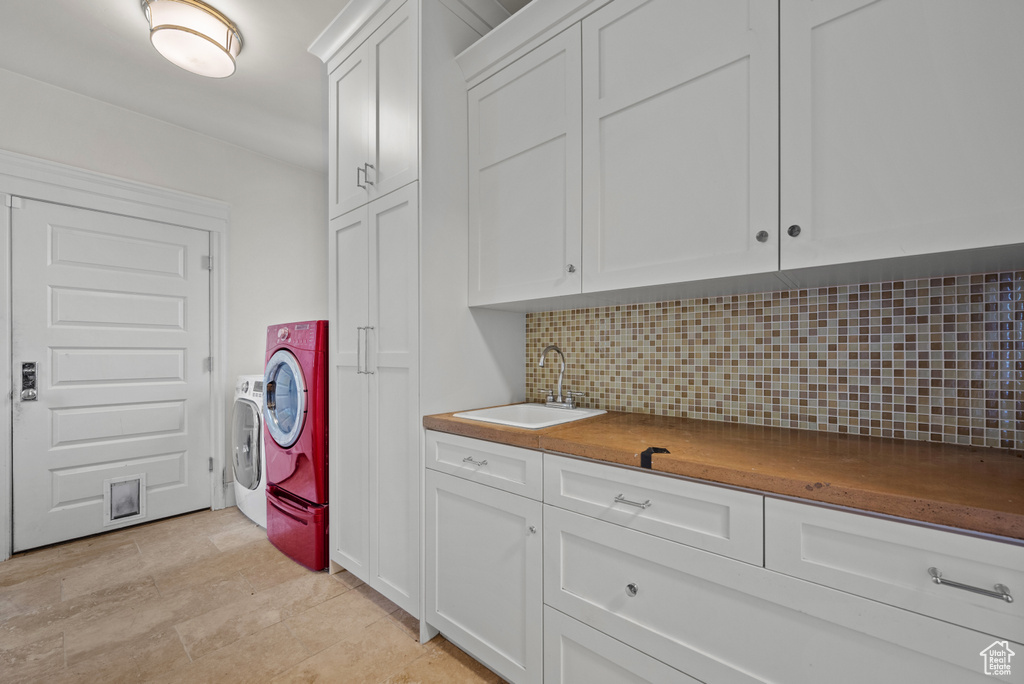 Clothes washing area with cabinet space, indoor wet bar, a sink, and washer and clothes dryer