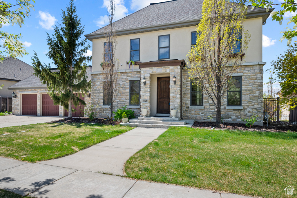 View of front facade featuring stone siding, stucco siding, and a front lawn