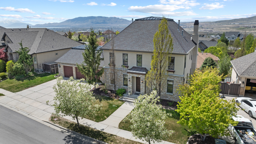 Traditional home with stone siding, an attached garage, a residential view, stucco siding, and fence