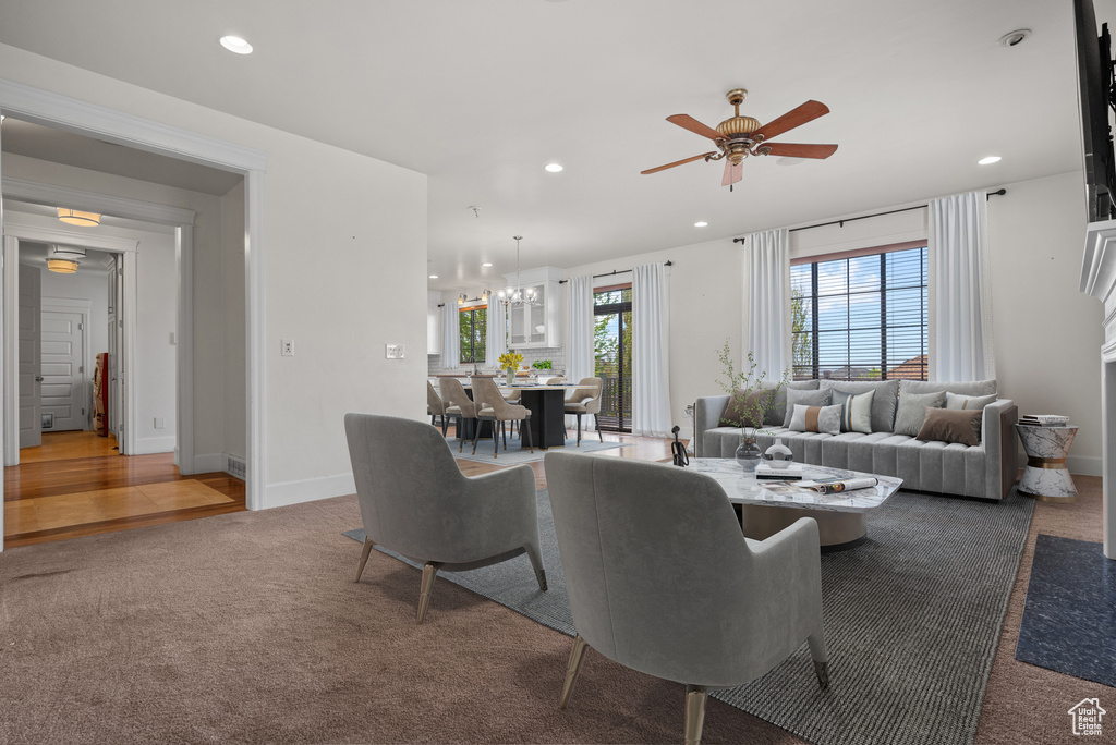 Carpeted living area with ceiling fan, recessed lighting, and a chandelier