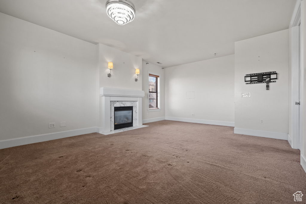 Unfurnished living room featuring carpet flooring, baseboards, and a high end fireplace