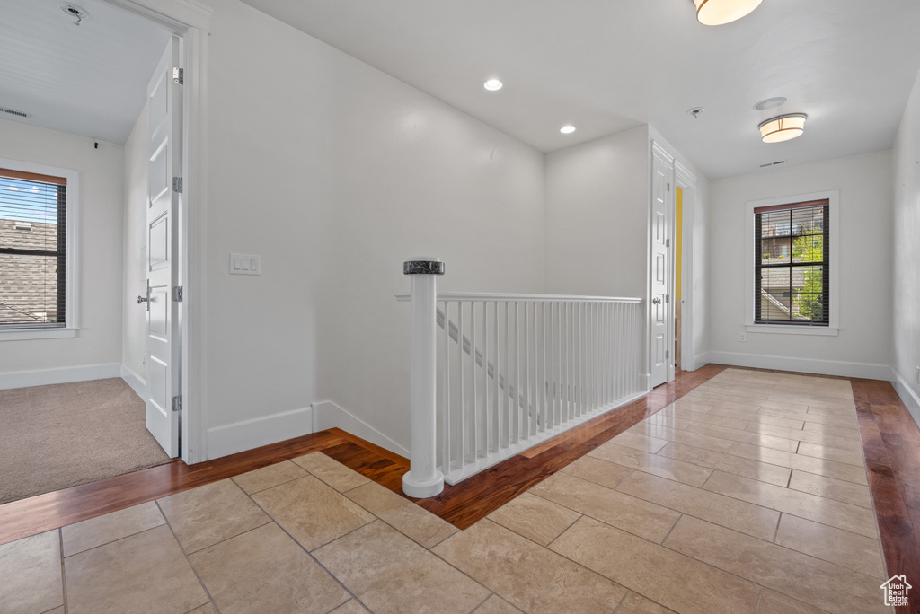 Hallway featuring baseboards, a wealth of natural light, tile patterned flooring, and recessed lighting