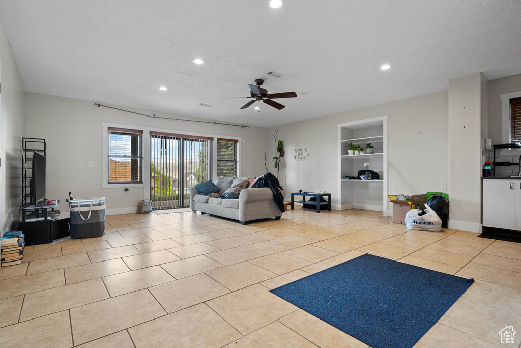 Living room with a ceiling fan, baseboards, recessed lighting, and built in shelves