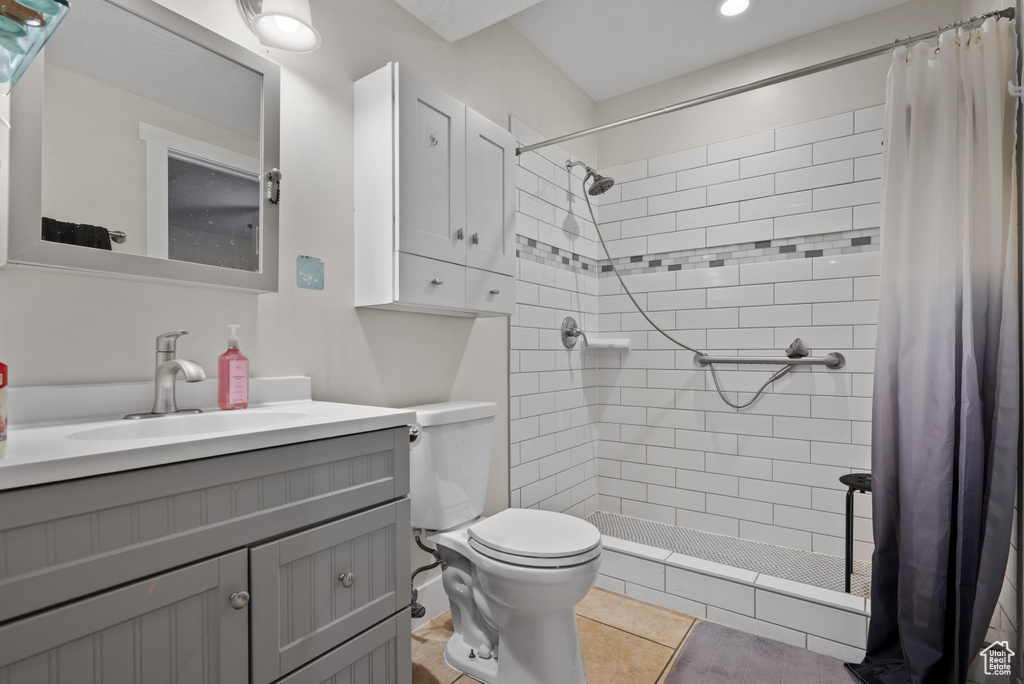 Bathroom featuring vanity, toilet, tiled shower, and recessed lighting