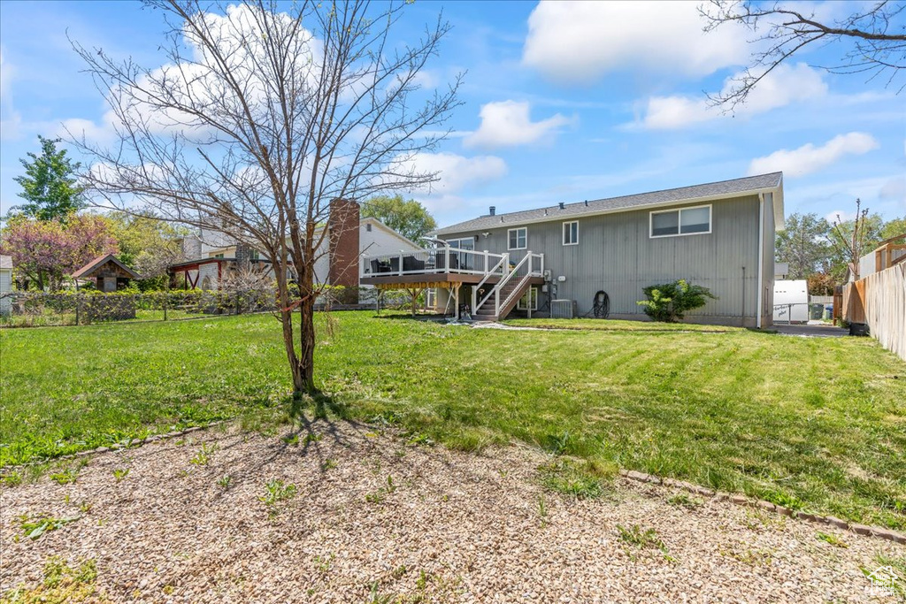 Back of house with a wooden deck, board and batten siding, stairway, a fenced backyard, and a yard