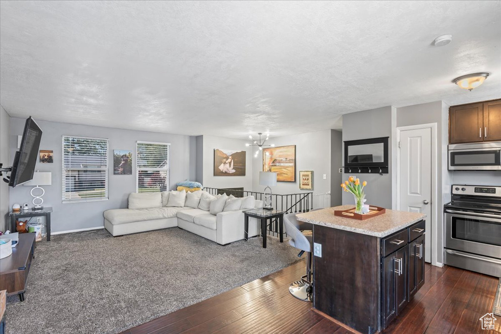 Living room with dark wood finished floors, a chandelier, baseboards, and a textured ceiling