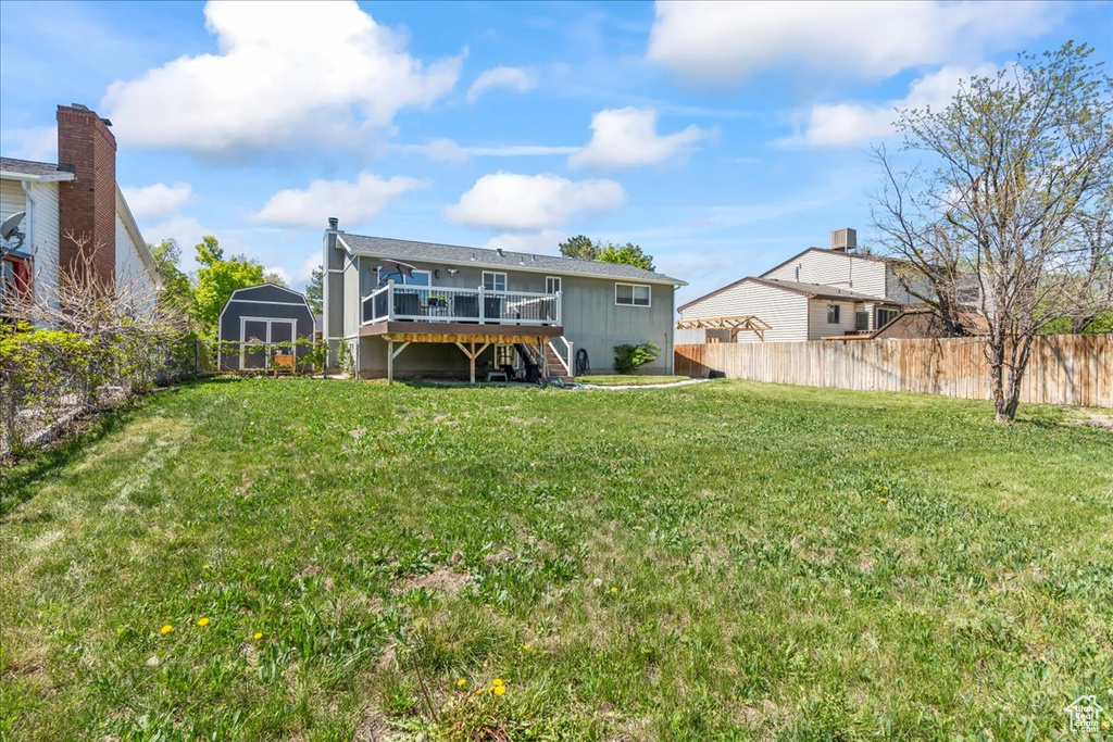 Back of house with an outdoor structure, a storage unit, stairway, a fenced backyard, and a wooden deck