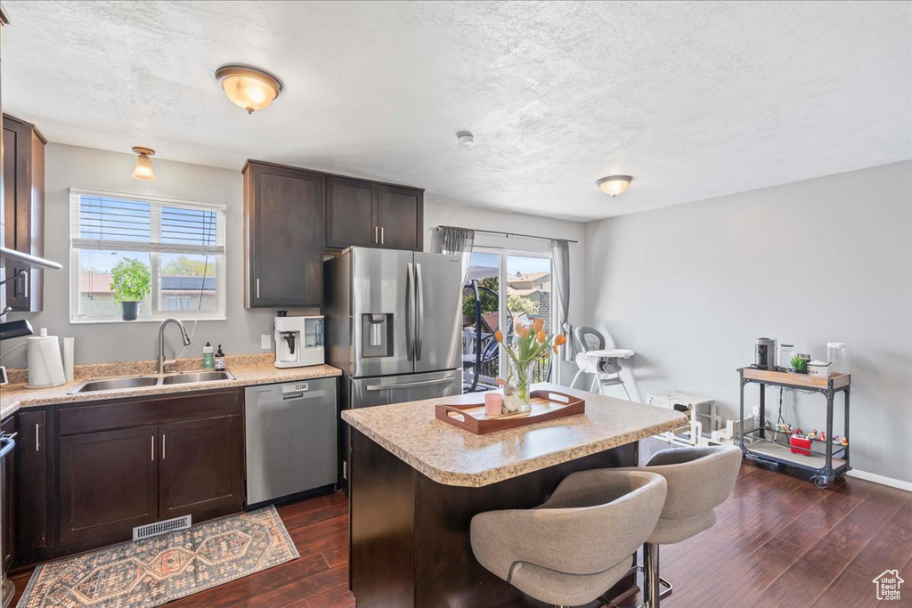 Kitchen featuring a sink, visible vents, dark wood-style flooring, a kitchen bar, and appliances with stainless steel finishes
