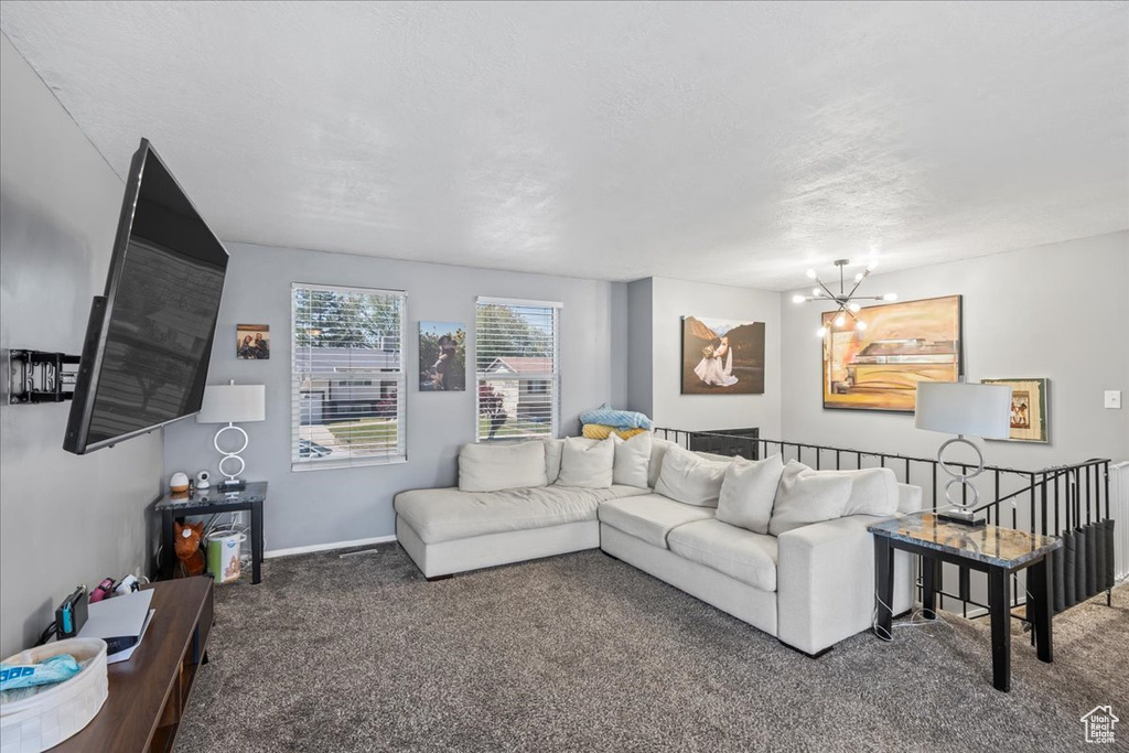 Carpeted living area featuring an inviting chandelier and baseboards
